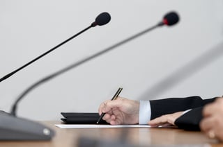 close up of conference meeting microphones and businessman writing