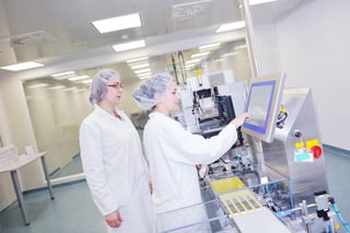 Two techs working on the monitor of a medical machine.
